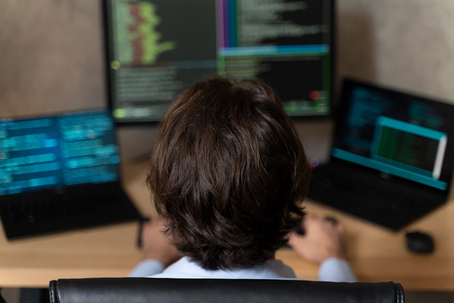 מתכנת יושב מול מסכים מרובים עם קוד פתוח, סביבה טכנולוגית ועבודה בתחום התכנות